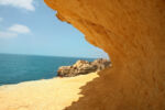 Image of an angular opening in sandstone looking out at beach and blue water - representing committing to the change and opening presents