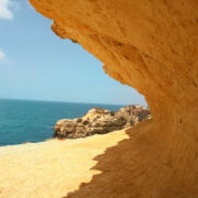 Image of an angular opening in sandstone looking out at beach and blue water - representing committing to the change and opening presents
