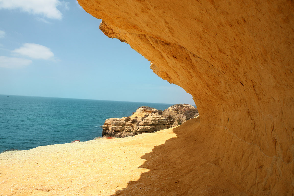 Image of an angular opening in sandstone looking out at beach and blue water - representing committing to the change and opening presents