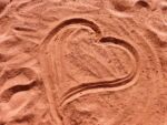 red-brown sand that a finger has drawn a heart in