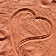 red-brown sand that a finger has drawn a heart in