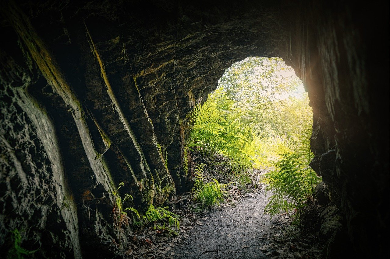 rock tunnel or cave opening to sunlight and grassy space