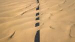 paved road almost totally covered by sand