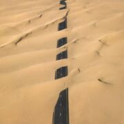 paved road almost totally covered by sand