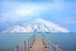 dock leading to blue water with beautiful snow-covered mountains in distance