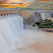 a dam overflow release on river in beautiful setting sun and hills
