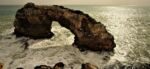 A rock arch over turbulent water in the sea