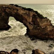 A rock arch over turbulent water in the sea
