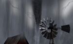 A farm windmill and barn roof in wind storm. Black and white photo.