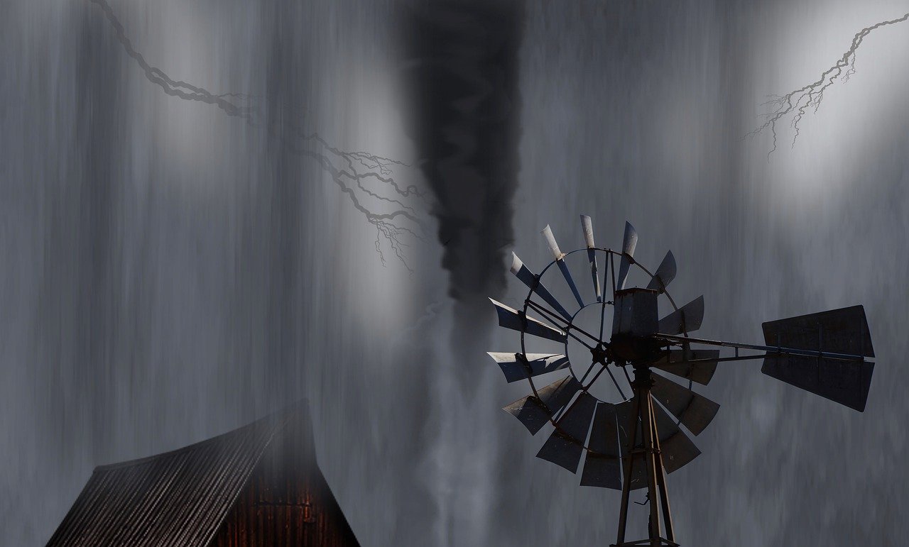 A farm windmill and barn roof in wind storm. Black and white photo.