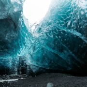 An ice cave with dramatic blue hues, leading to a white opening.