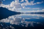 Sky, clouds and mountain reflected in still water.