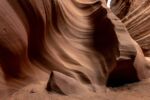 A swirling red rock formation with a small opening.