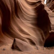 A swirling red rock formation with a small opening.