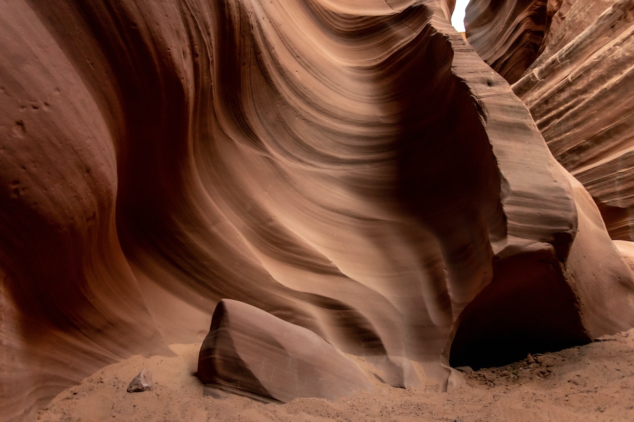 A swirling red rock formation with a small opening.