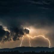 Dark sky with gray and gold tones with clouds and bolts of lightning