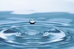 A drop of blue water falling into blue water and creating circles.