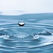 A drop of blue water falling into blue water and creating circles.