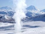 A fumarole rising in a mountainous, snowy landscape