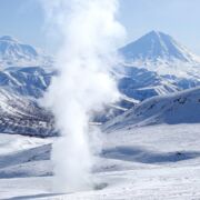 A fumarole rising in a mountainous, snowy landscape