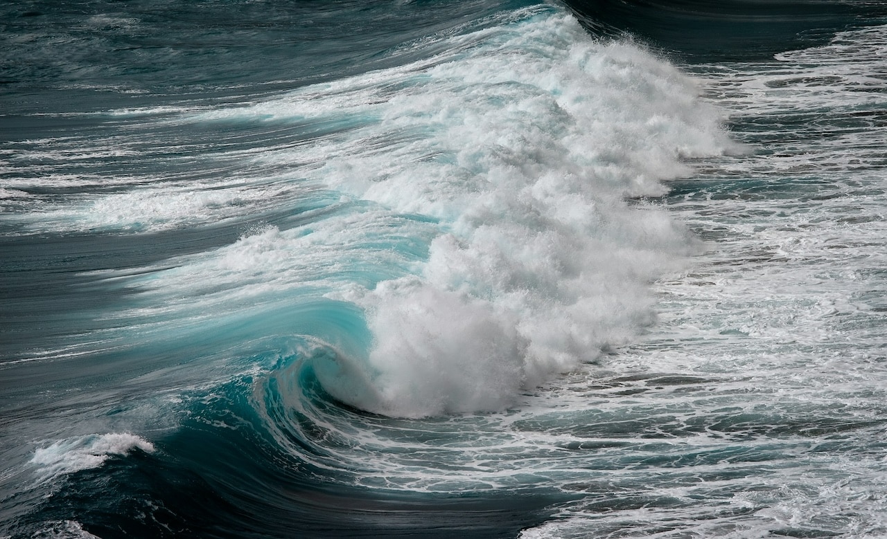 A large, breaking ocean wave - blue water with white caps.