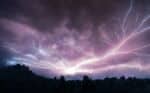 Dramatic lightning in a dark blue and purple sky.