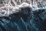 A chaotic, swelling blue ocean wave.