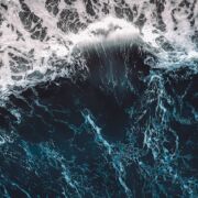 A chaotic, swelling blue ocean wave.