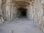 A tannish brown cave opening with a long, dark entryway.
