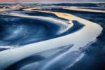 A sandy area invaded by water, creating formations in the sand.