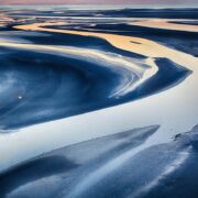 A sandy area invaded by water, creating formations in the sand.