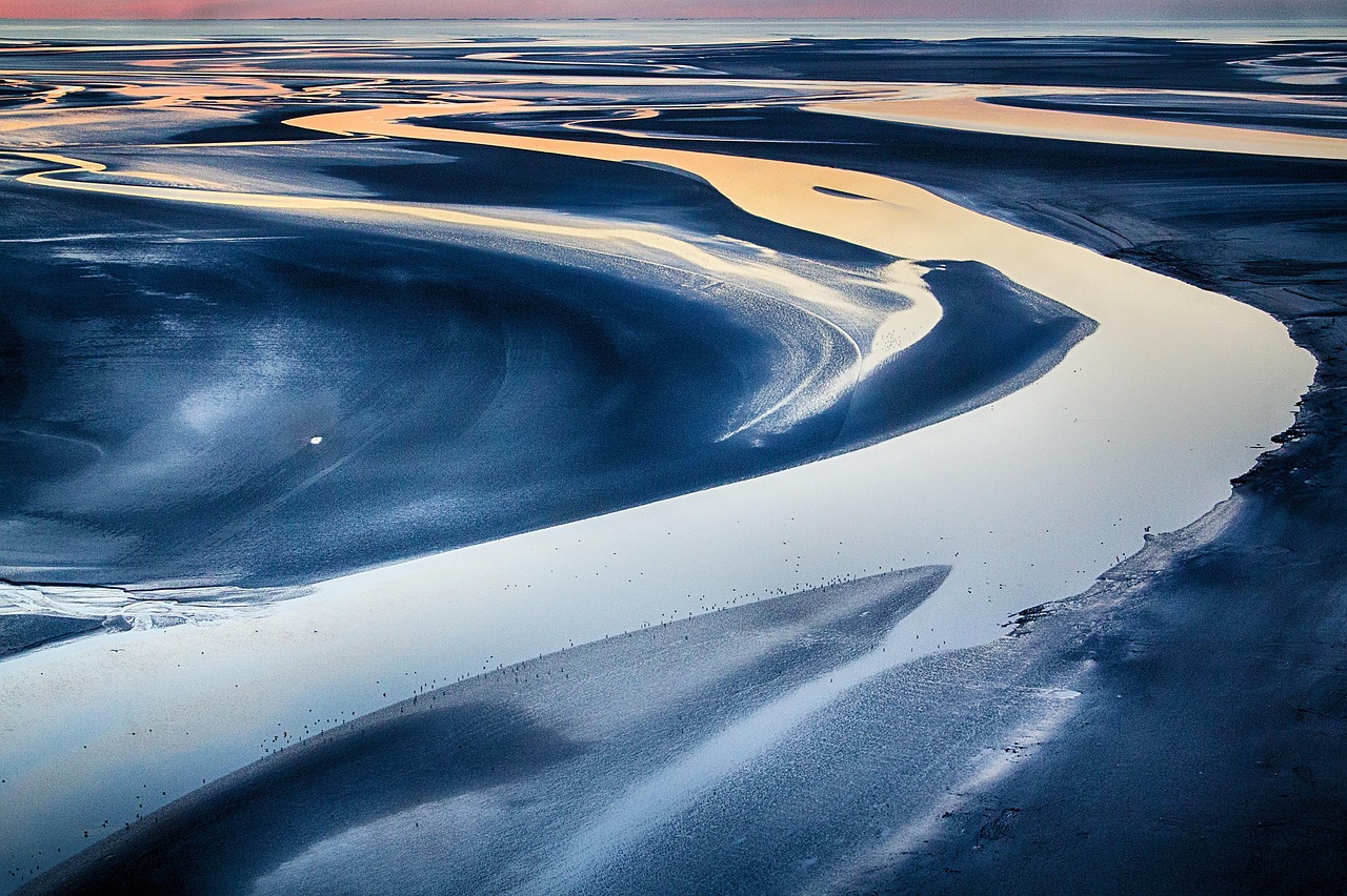 A sandy area invaded by water, creating formations in the sand.