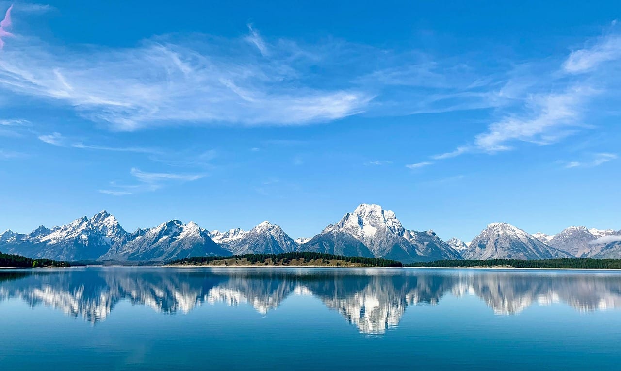 Snow-capped Grand Teton mountain range perfectly reflected in a body of water