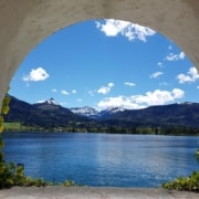 An opening through a cement tunnel to a beautiful and peaceful scene of a lake, green hills and blue sky.