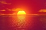 A bright yellow sun setting over water wuith orang hues.