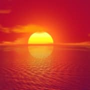 A bright yellow sun setting over water wuith orang hues.