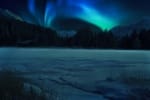 A beautiful scene on a partly frozen lake with mountains and brilliant blue and green northern lights on a dark night.