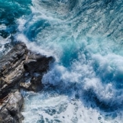 Fast blue waves crashing on gray rocks