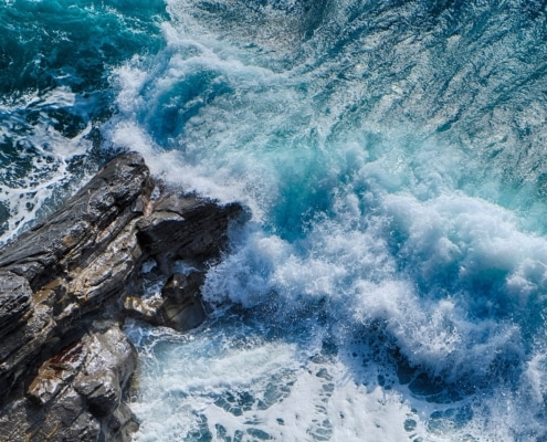 Fast blue waves crashing on gray rocks