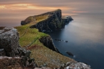A grass-covered rock peninsula jutting into the ocean.
