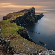 A grass-covered rock peninsula jutting into the ocean.