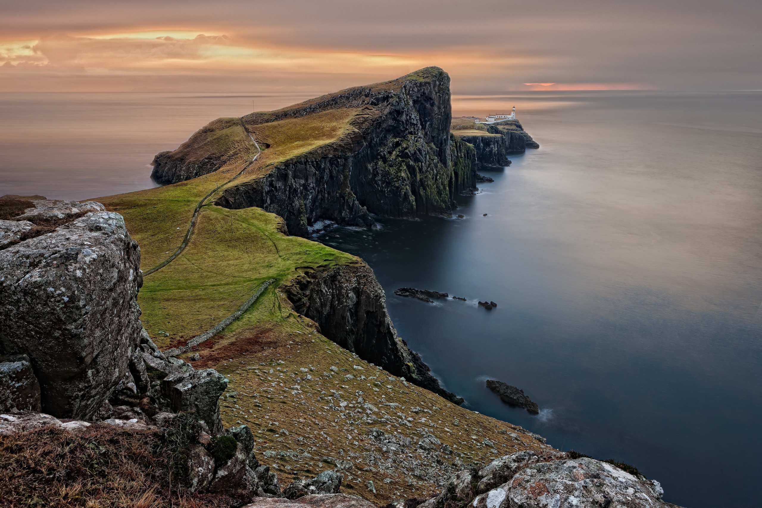 A grass-covered rock peninsula jutting into the ocean.