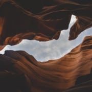 Looking up through an Opening between red rocks to a gray sky