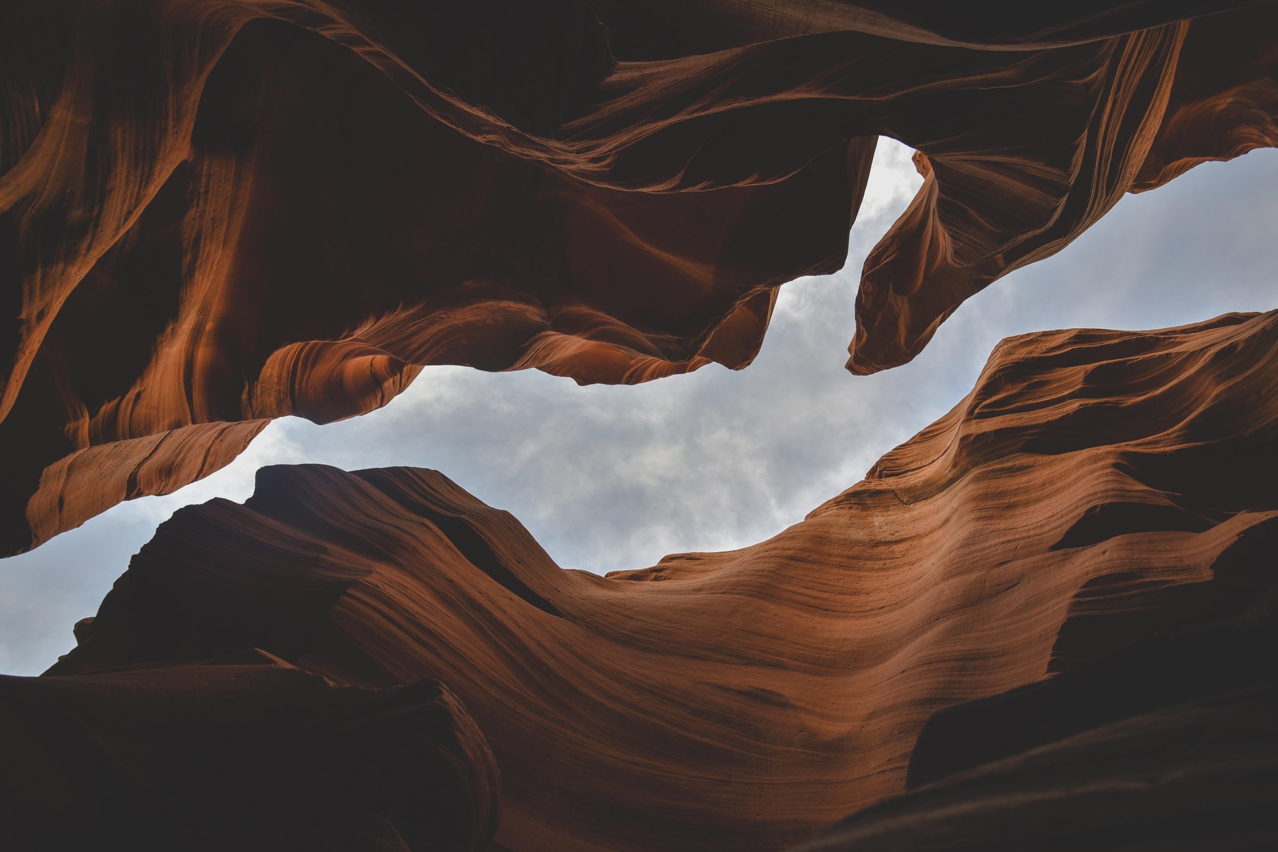 Looking up through an Opening between red rocks to a gray sky