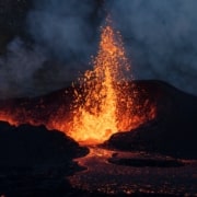 Fire and lava spewing up from an active volcano in a dark night.