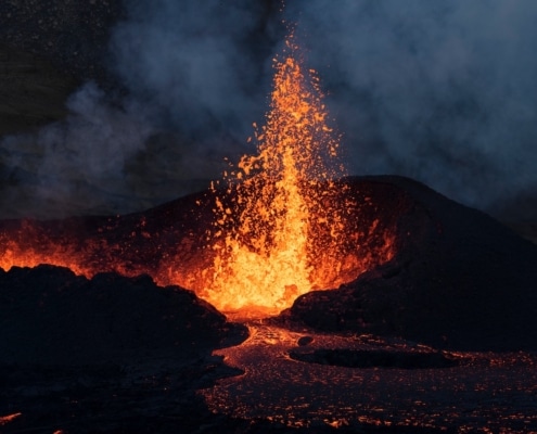 Fire and lava spewing up from an active volcano in a dark night.
