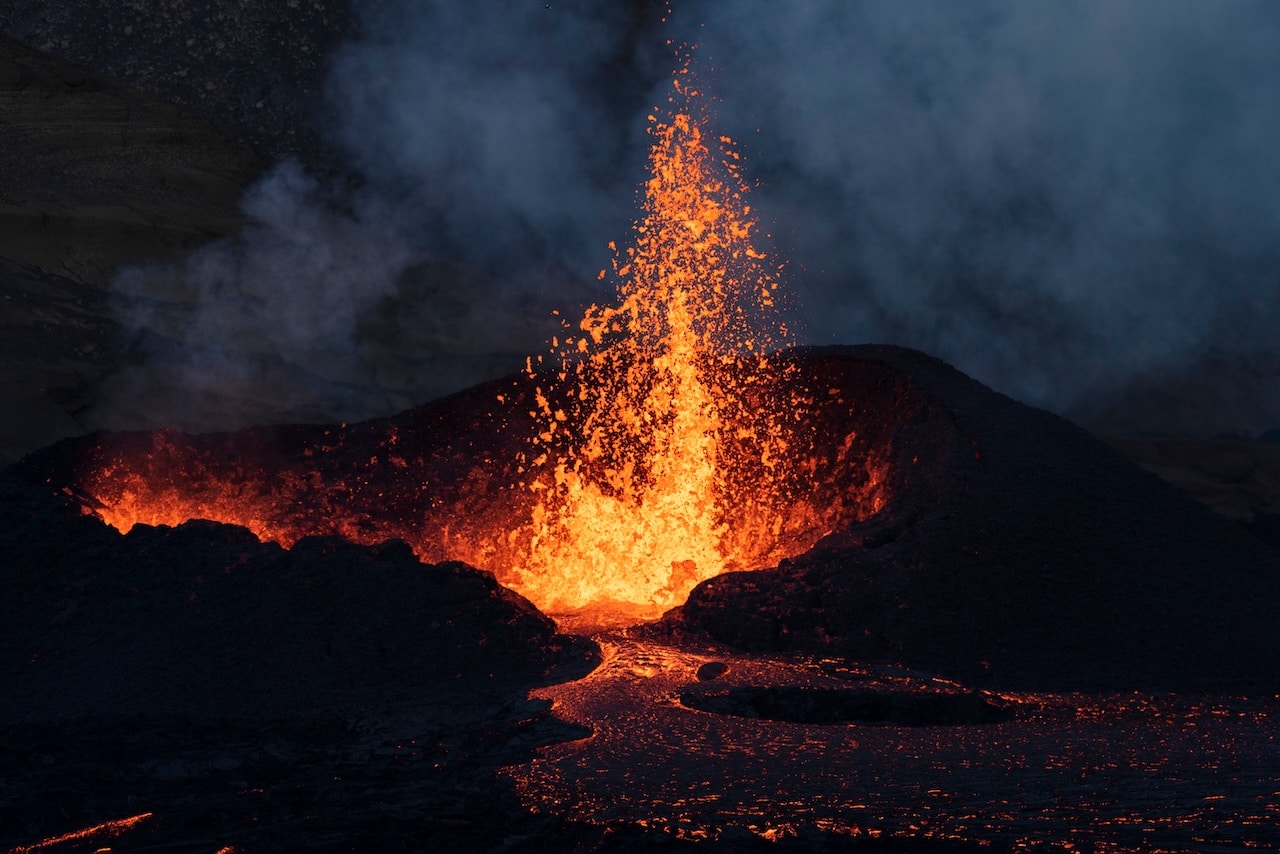 Fire and lava spewing up from an active volcano in a dark night.